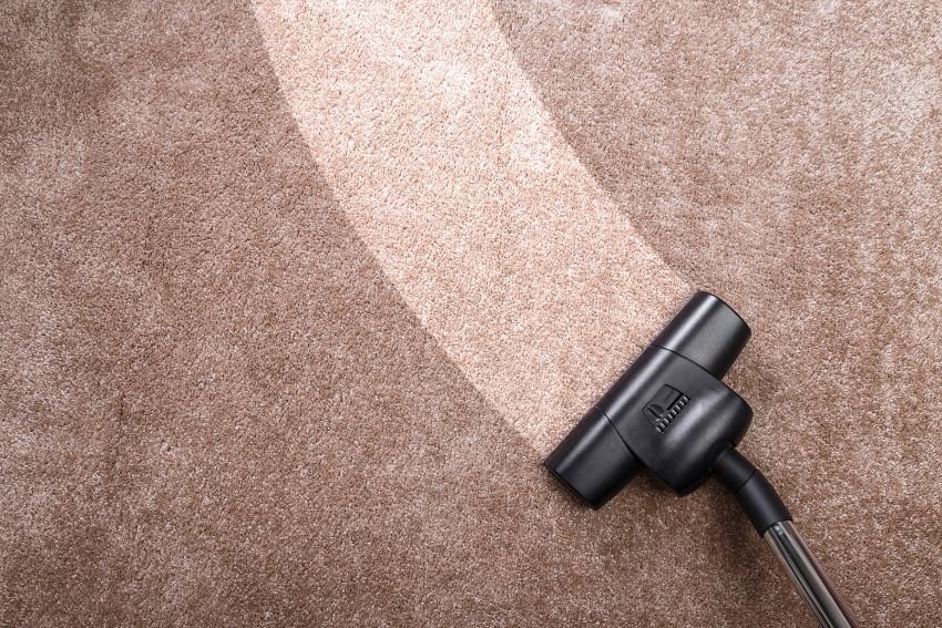 A vacuum cleaner actively cleaning a carpet, representing a mold removal service in Houston, TX.