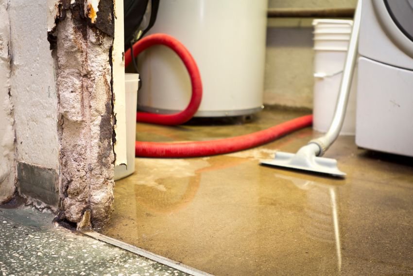 A water heater alongside a hose in a room, representing a water damage restoration service based in Houston, TX.
